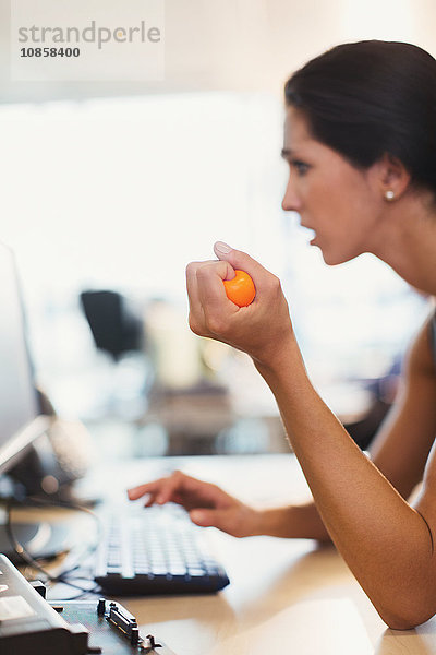 Geschäftsfrau quetscht Stressball am Computer im Büro