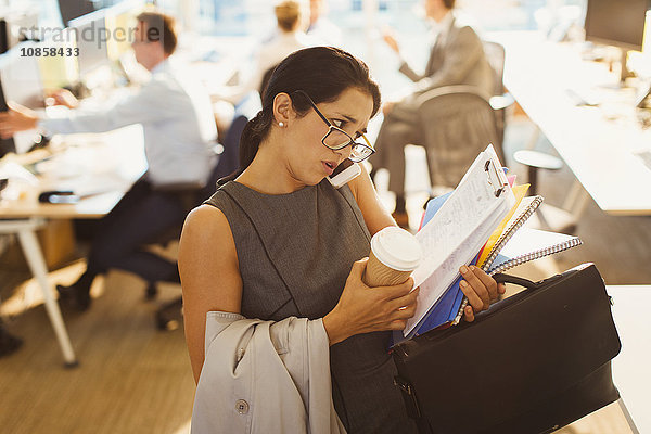 Gestresste Geschäftsfrau kämpft mit Multitasking im Büro