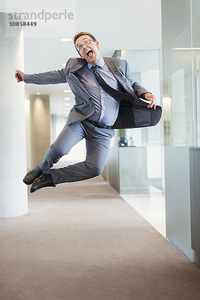 Überschwänglicher Geschäftsmann springt vor Freude in den Büroflur