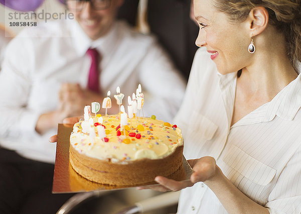 Lächelnde Geschäftsfrau mit Geburtstagskuchen und Kerzen