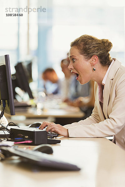 Schockierte Geschäftsfrau bei der Arbeit am Computer im Büro