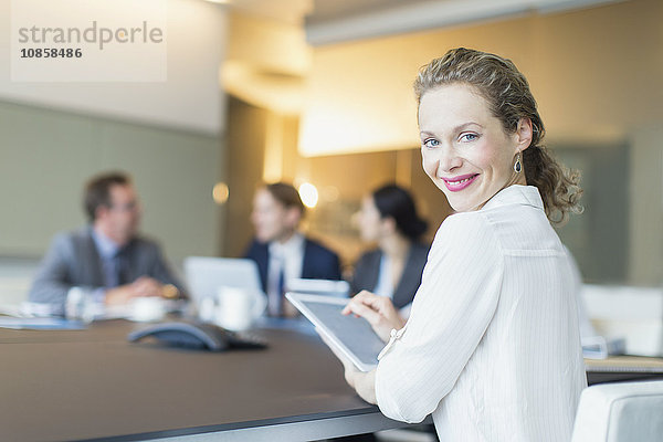 Portrait lächelnde Geschäftsfrau mit digitalem Tablett in Konferenzraumbesprechung