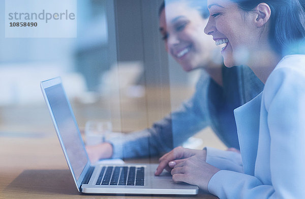 Lachende Geschäftsfrauen bei der Arbeit am Laptop