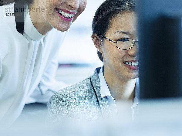 Lächelnde Geschäftsfrauen bei der Arbeit am Computer im Büro