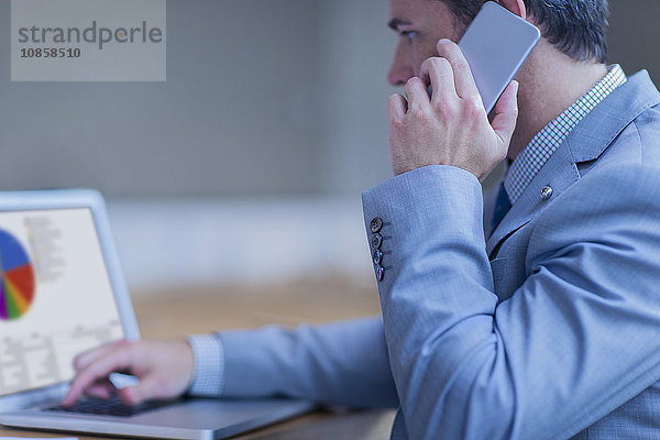 Geschäftsmann beim Telefonieren und Arbeiten am Laptop