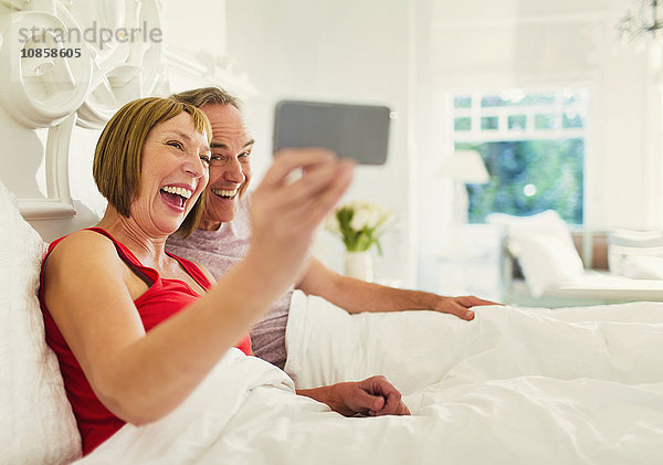 Enthusiastisch reif ein Paar  das Selfie im Bett nimmt.
