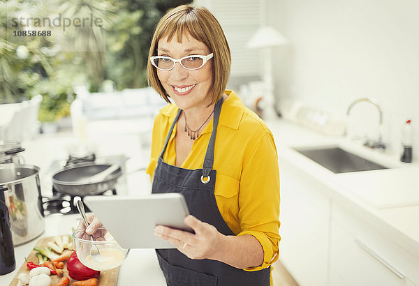 Portrait lächelnde reife Frau mit digitalem Tablettenkochen in der Küche