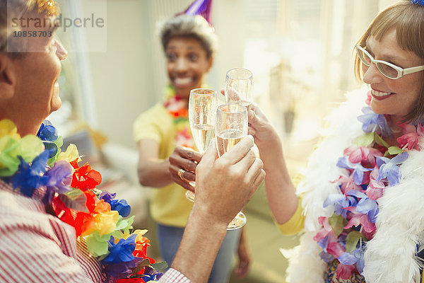 Verspielte  reife Freunde in Federboas und Champagnerflöte mit Leis-Toast