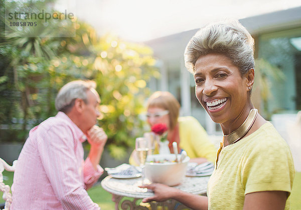 Portrait lächelnde reife Frau beim Mittagessen mit Freunden im Garten