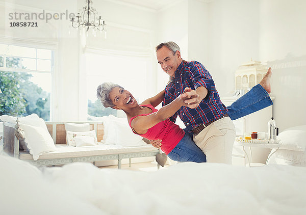 Verspieltes reifes Paar tanzt im Wohnzimmer