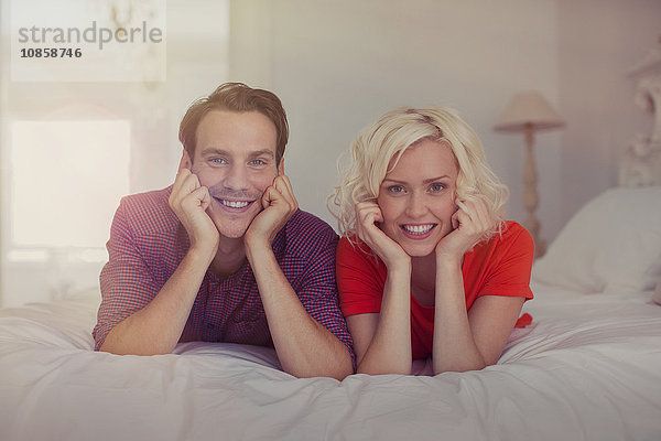 Portrait lächelndes Paar mit Kopf in den Händen auf dem Bett