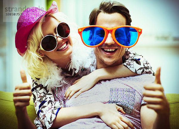 Porträt eines verspielten Paares mit Sonnenbrille und Hut mit Daumen nach oben