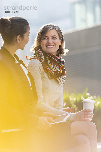 Geschäftsfrauen mit digitalem Tablett und Kaffee im Freien