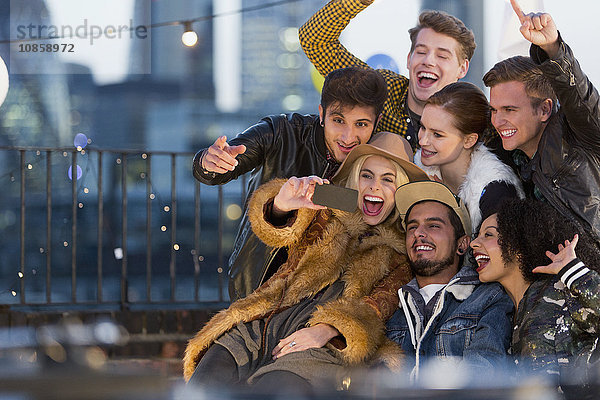 Enthusiastische junge erwachsene Freunde nehmen Selfie auf der Dachparty
