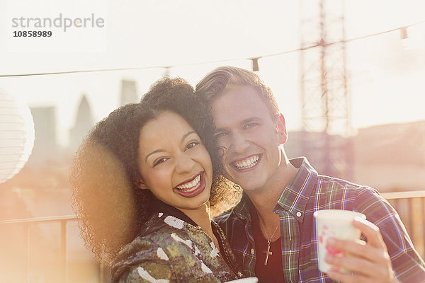 Portrait lächelndes junges Paar genießt Dachparty