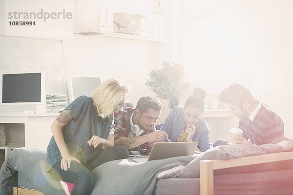 Studenten studieren am Laptop am Bett im sonnigen Schlafzimmer