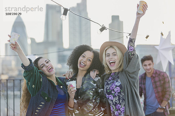 Portrait überschwängliche junge Frauen  die auf der Dachparty jubeln und trinken