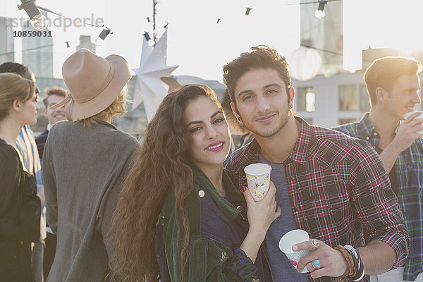 Portrait lächelndes junges Paar beim Trinken auf der Dachparty