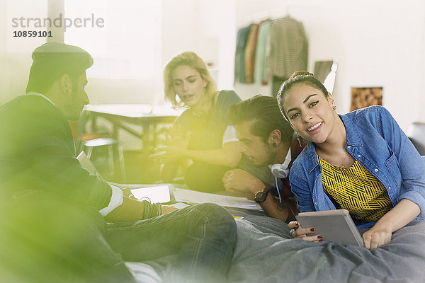 Porträt eines lächelnden Studenten  der mit Freunden im Bett studiert.