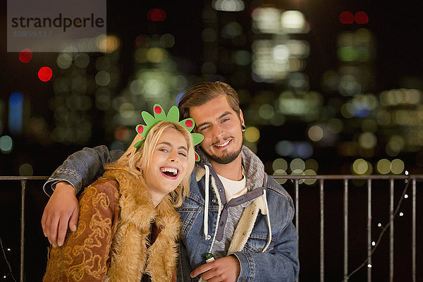 Portrait lächelndes junges Paar genießt nächtliche Dachparty