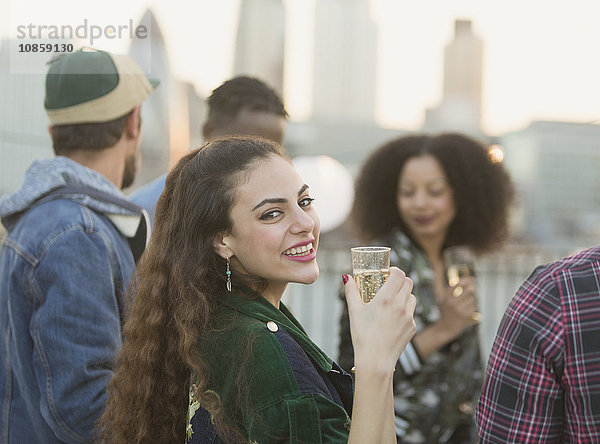 Portrait lächelnde junge Frau trinkt Champagner auf der Dachparty