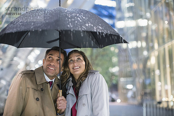 Geschäftsmann und Geschäftsfrau beobachten Regen unter dem Regenschirm