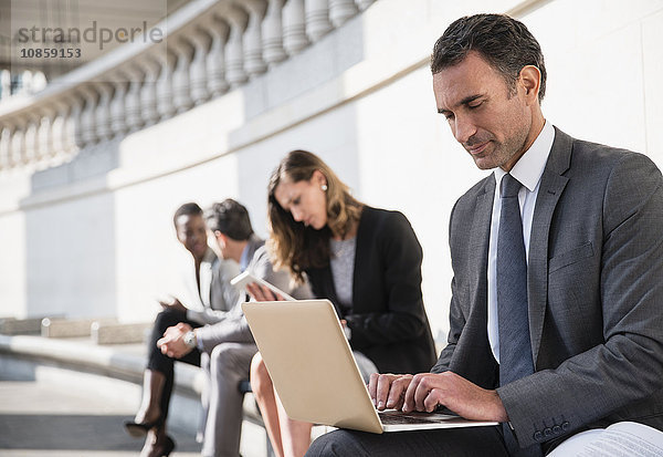 Corporate Geschäftsmann mit Laptop auf der Bank im Freien