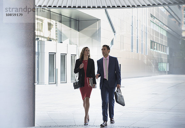 Geschäftsmann und Geschäftsfrau  die außerhalb des Gebäudes spazieren gehen.