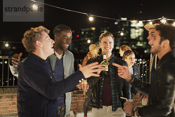 Junge Männer beim Trinken und Lachen auf der Dachparty