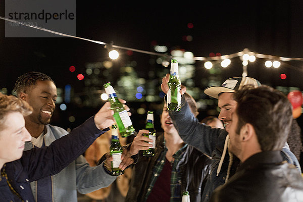 Junge Männer trinken Bier und tanzen auf der Dachparty