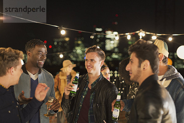 Junge Männer trinken Bier und reden auf der Dachparty