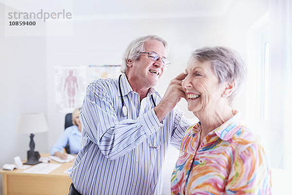 Arzt untersucht das Ohr einer älteren Frau bei der Untersuchung