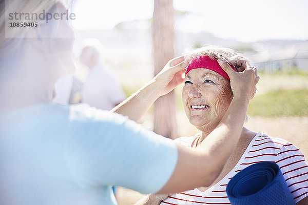 Yogalehrerin beim Anpassen des Kopfbandes der Seniorin