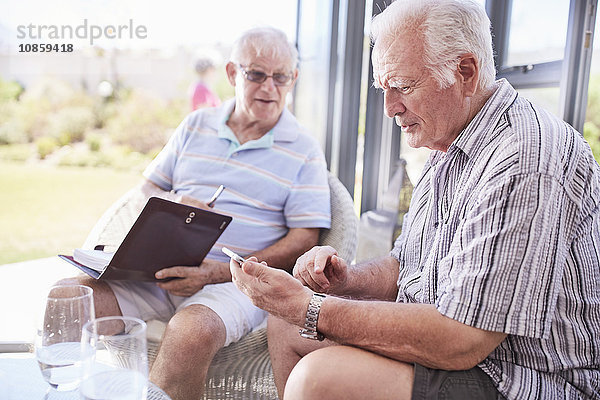 Senior Männer SMS mit Handy auf der Terrasse