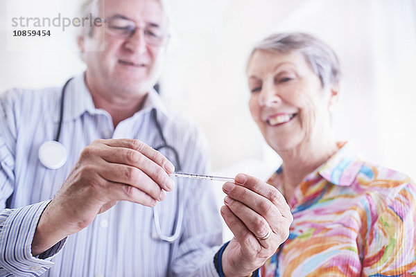 Arzt zeigt Thermometer der älteren Frau