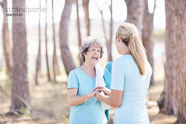 Seniorin und Yogalehrerin im sonnigen Park