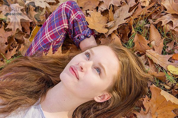 Teenager-Mädchen auf Herbstlaub liegend  Nahaufnahme