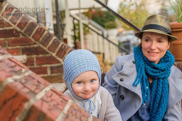 Mutter und kleiner Sohn sitzen zusammen auf der Eingangstreppe