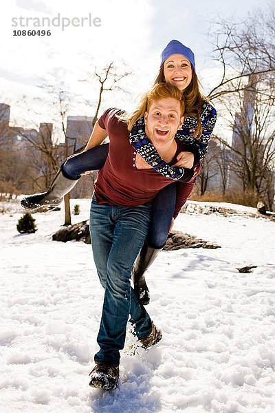 Junger Mann gibt seiner Freundin ein Huckepack im verschneiten Central Park  New York  USA