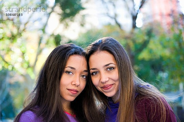 Zwillingsschwestern lächeln im Park