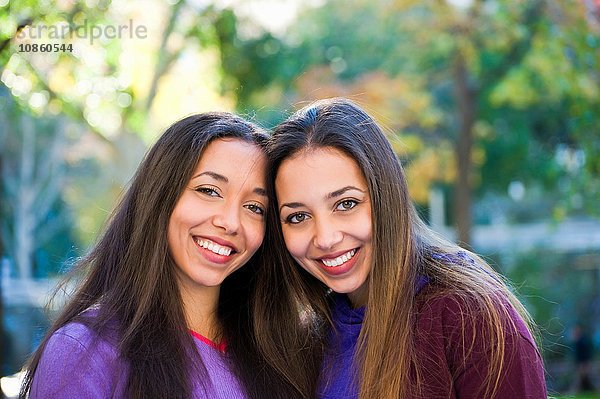 Zwillingsschwestern lächeln im Park