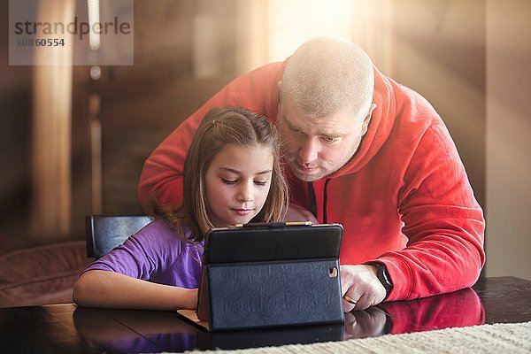 Vater und Tochter benutzen drahtloses digitales Tablet zu Hause