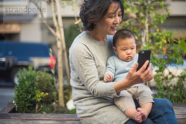 Großmutter zeigt ihrem Enkel im Freien ein Smartphone