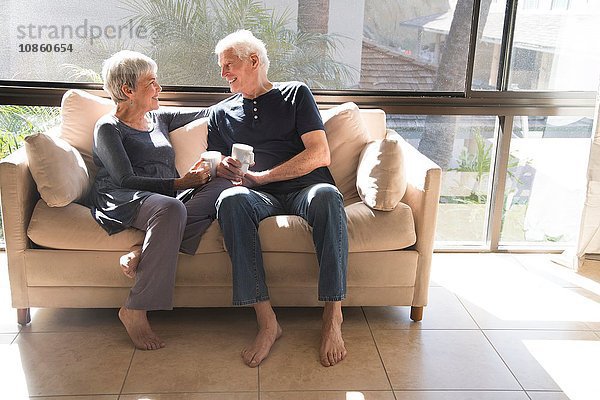 Älteres Ehepaar  entspannt auf dem Sofa  von Angesicht zu Angesicht sitzend  lächelnd