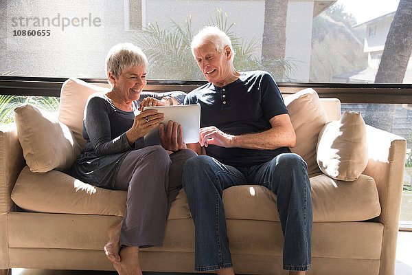 Älteres Ehepaar  entspannen sich auf dem Sofa und schauen auf das digitale Tablett
