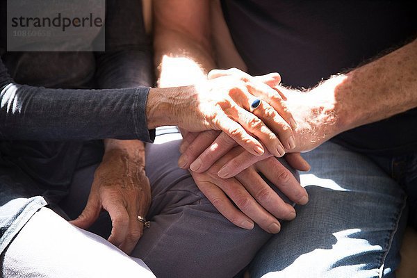 Älteres Paar sitzt zusammen  berührt sich an den Händen  Mittelteil  Nahaufnahme