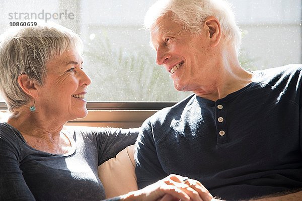 Älteres Ehepaar sitzt zusammen  von Angesicht zu Angesicht  lächelnd