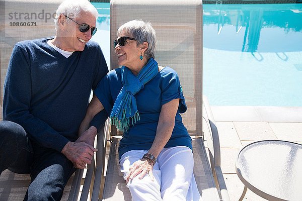 Älteres Ehepaar entspannt sich auf Liegestühlen am Pool