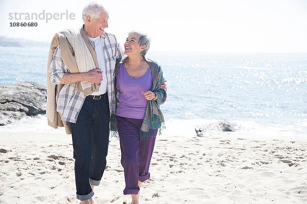 Älteres Ehepaar geht am Strand spazieren  lächelnd