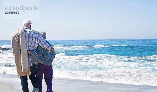 Älteres Paar am Strand stehend  Blick aufs Meer  Rückansicht